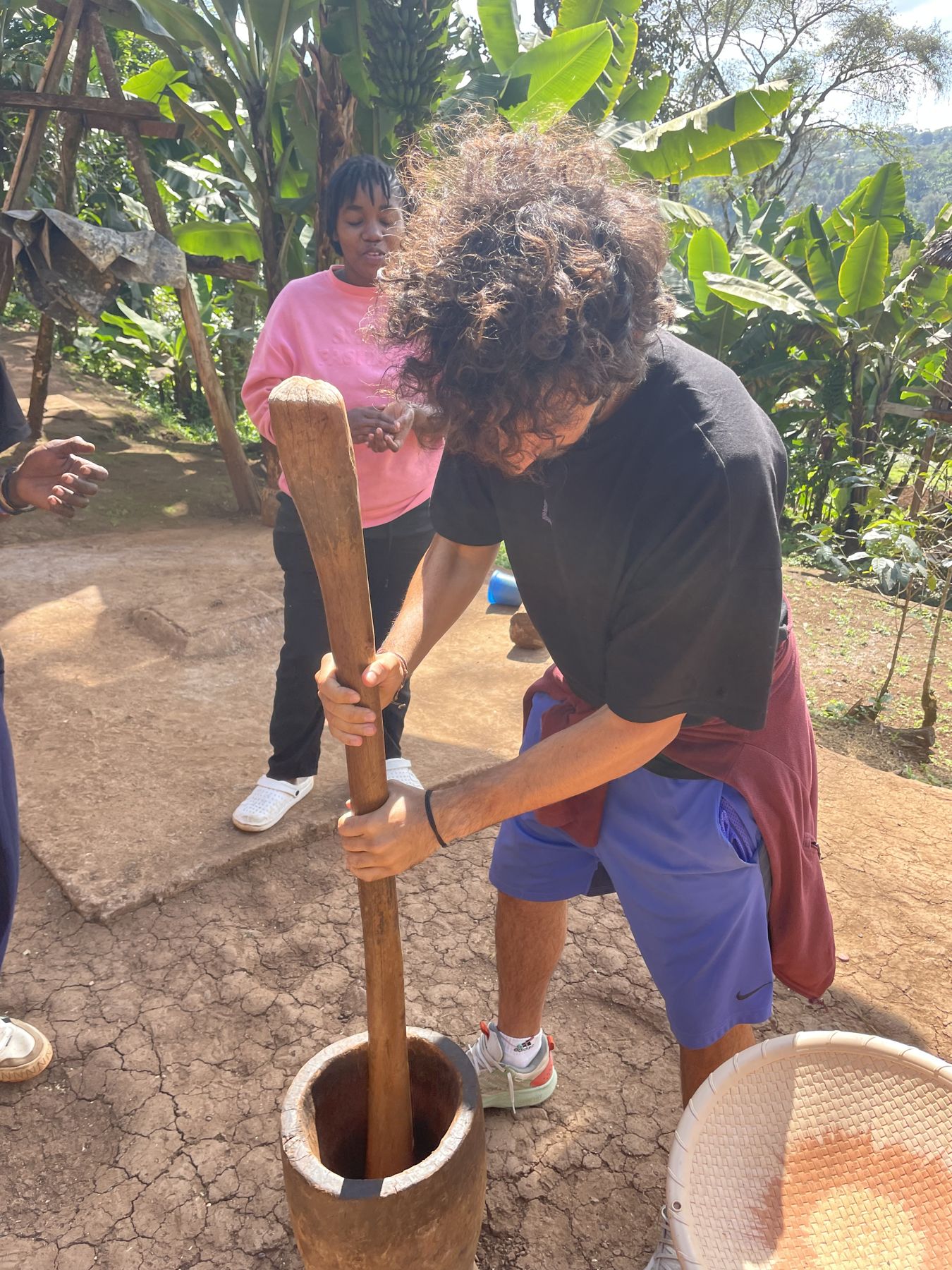 A guest pounding roasted coffee in a wooden mortar